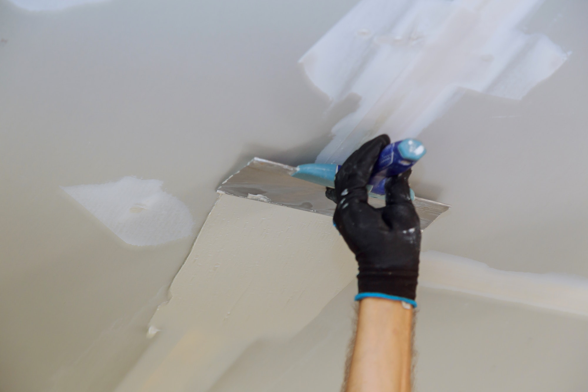 Closeup of a man aligning a wall with spatula and plastering gypsum cardboard wall